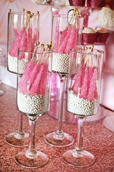 four wine glasses filled with white and pink candy