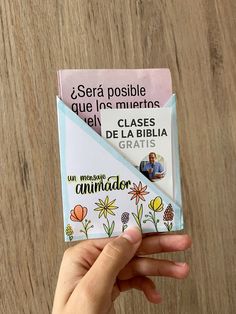 a person holding up a small card with flowers on it and the words congratulations written in spanish