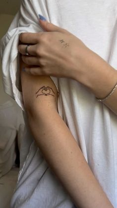 a woman with a tattoo on her arm holding onto another person's arm and wearing a white t - shirt