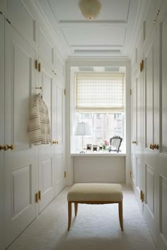 a room with white cabinets and a bench in the corner, next to a window