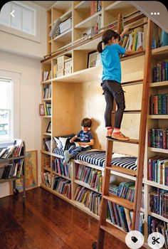 two children are climbing up and down the bookshelves in this room, while another child is on top of the ladder