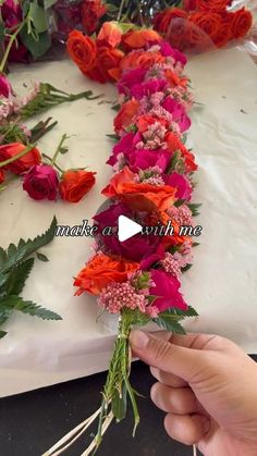 someone is arranging flowers on a table with white frosting and pink and red flowers