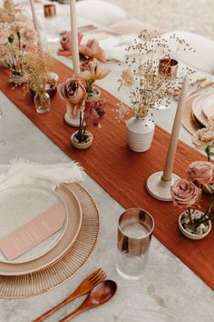 the table is set with pink and white flowers, candles, and place settings for an elegant dinner party