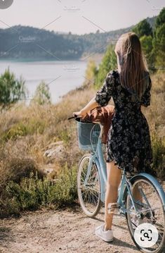 a woman riding a bike on the side of a road next to a body of water