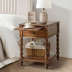 a small wooden table with a basket underneath it and a lamp on the side next to it