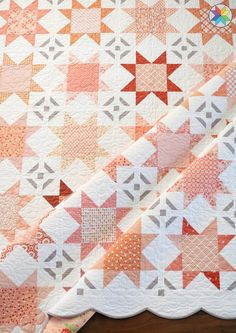 an orange and white quilt on a wooden table