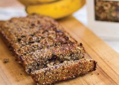 a loaf of banana nut bread sitting on top of a wooden cutting board next to bananas