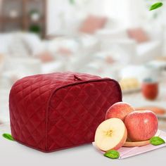 a red bag sitting on top of a table next to apples