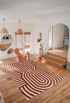 a living room with wooden floors and white walls, an area rug that looks like a maze