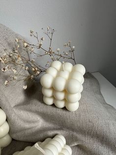 a bunch of white balls sitting on top of a bed next to a vase filled with flowers