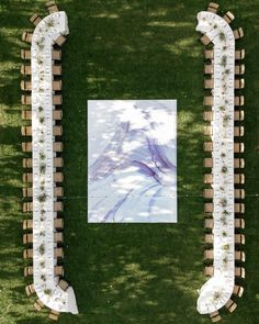 an overhead view of two rows of tables and chairs in the grass