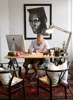 a man sitting at a desk in front of a computer on top of a rug