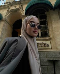 a mannequin wearing sunglasses and a headscarf in front of a building