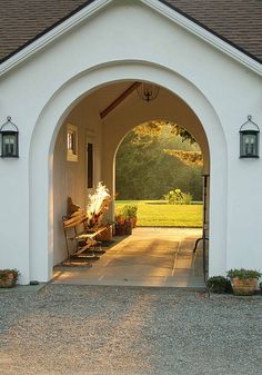 an arched entrance to a white house with potted plants