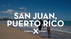 two people standing on the beach looking out at the ocean and buildings in the distance