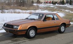 an orange car is parked on the side of the road