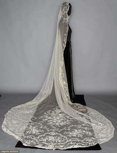 the back of a wedding dress with a veil on display in front of a mannequin