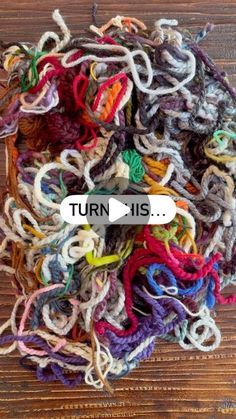 a pile of colorful yarn sitting on top of a wooden floor next to a sign that says, turn his