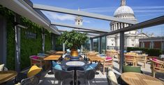 an outdoor dining area with tables and chairs on the roof terrace overlooking st paul's cathedral