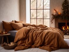 a bed with brown sheets and pillows next to a fire place in front of a christmas tree