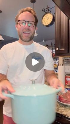 a man standing in front of a large pot with meat on it and holding the lid open