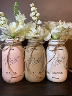 three mason jars with white flowers in them