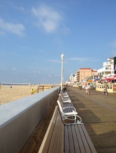 benches along the boardwalk on a sunny day in front of beachfront shops and restaurants