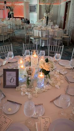 the table is set with white flowers, candles and place settings for guests to sit at