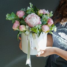 a woman holding a bouquet of flowers in her hand with the ribbon tied around it