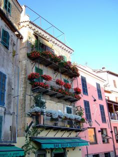 an old building with flowers on the balconies and plants growing out of it