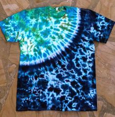 a blue and green tie - dyed t - shirt laying on top of a wooden floor