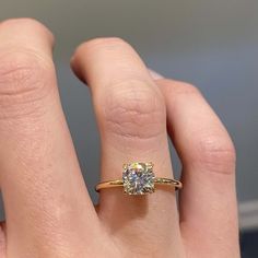 a woman's hand with a diamond ring on top of her finger, showing the center stone