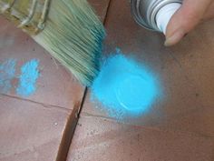 a person is using a brush to paint the floor with blue powder on top of it