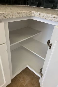 an empty white kitchen cupboard with marble counter tops