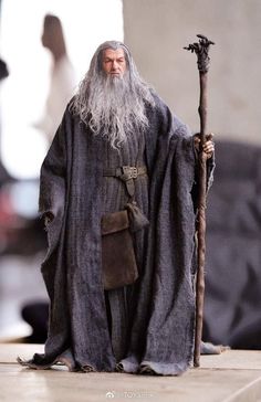 a man with long gray hair and beard holding a stick in one hand while standing on a platform