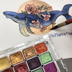 a watercolor painting of a dolphin with flowers on it's head and some paint in its mouth