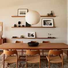 a dining room table with chairs and pictures on the wall above it, along with other furniture