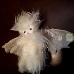 a white stuffed animal with feathers on it's back and wings spread out to the side