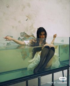 a woman sitting on top of a glass table with her arms out and legs crossed