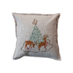 an embroidered pillow with two deers and a christmas tree on the front, sitting on a white background