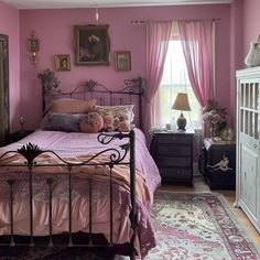 a bed room with a neatly made bed next to a dresser and window covered in pink curtains