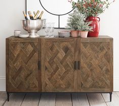 a wooden cabinet sitting next to a mirror and vase on top of a hard wood floor