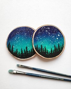 two coasters with trees painted on them and paintbrushes next to one another