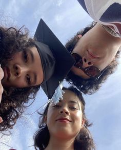 four people wearing graduation caps looking up at the sky with their heads tilted to the side