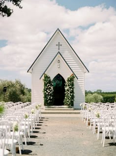 an outdoor wedding venue with white chairs and flowers on the aisle leading up to the door