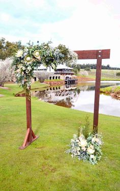 an outdoor ceremony setup with flowers and greenery on the grass next to a lake