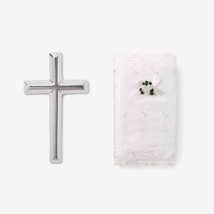 a cross and napkin on a white surface with a small flower in the center next to it