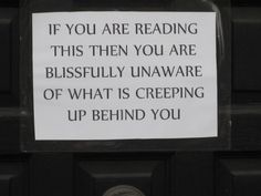 a sign posted on the front door of a building that says if you are reading this then you are blissfully unaware of what is creping up behind you