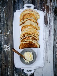 a white plate topped with lots of pancakes and butter