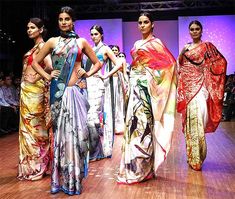 several women in sari walking down the runway at a fashion show with purple lighting behind them